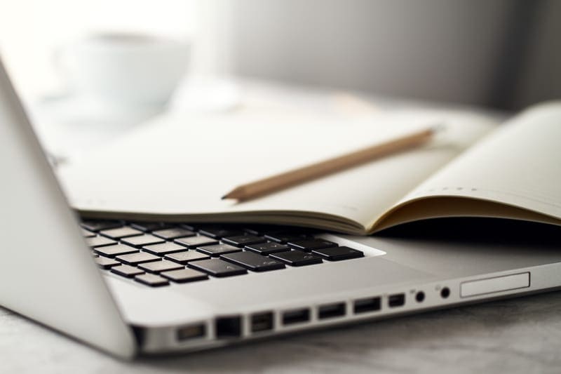 Ordinateur portable avec carnet ouvert et stylo, représentant la création d'un site web pour auteur
