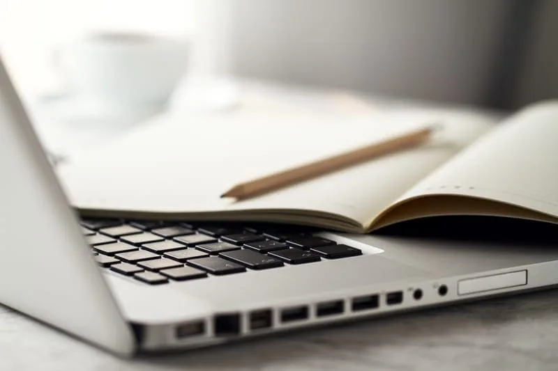 Ordinateur portable avec carnet ouvert et stylo, représentant la création d'un site web pour auteur