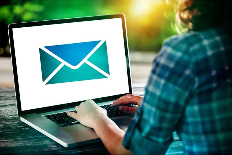 Personne tapant sur un ordinateur portable avec une icône d’email affichée à l’écran.