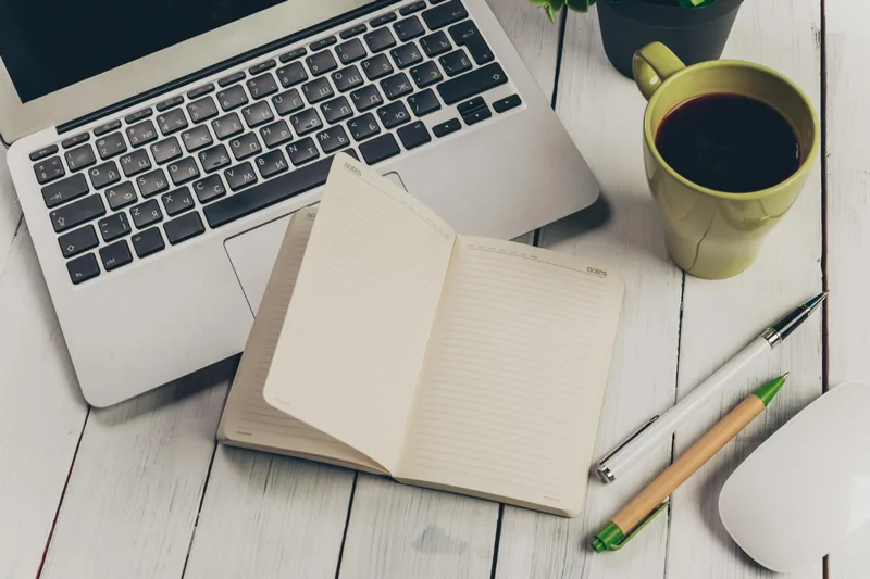 Bureau d’auteur avec ordinateur, carnet et café, symbolisant un espace de travail inspirant pour écrire et gérer un site web.
