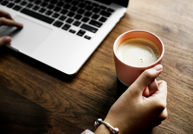 Tasse de café posée devant un ordinateur, symbole de pause et de surcharge mentale en freelance