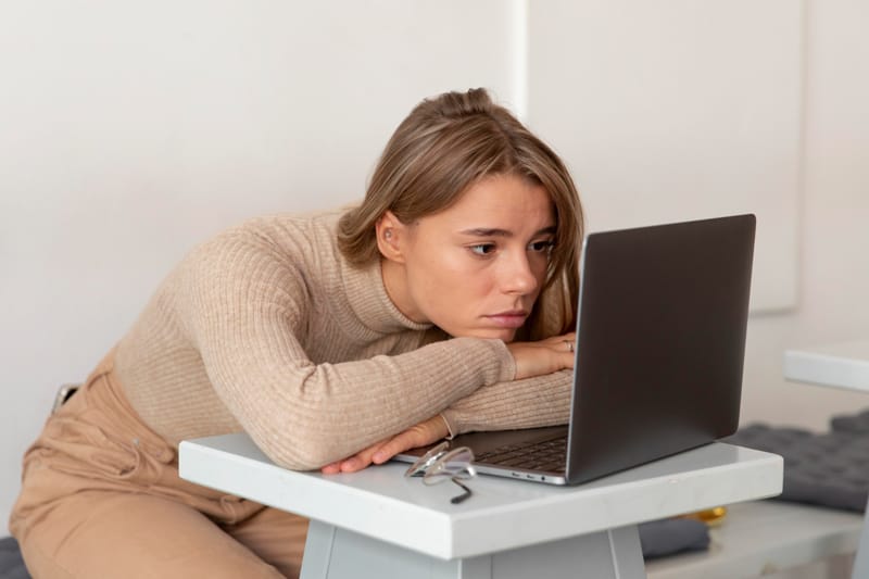 Femme fatiguée appuyée sur la table devant son ordinateur portable