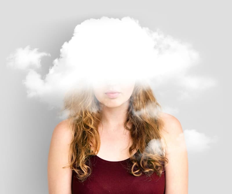 Femme avec la tête dans un nuage, représentant la confusion mentale ou la surcharge d’informations.