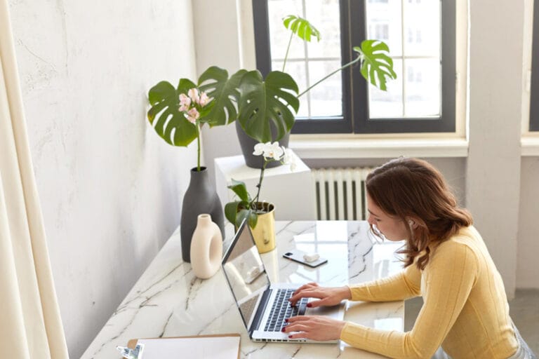 Femme travaillant sur un ordinateur portable dans un bureau lumineux, symbolisant l’optimisation des images pour le web.