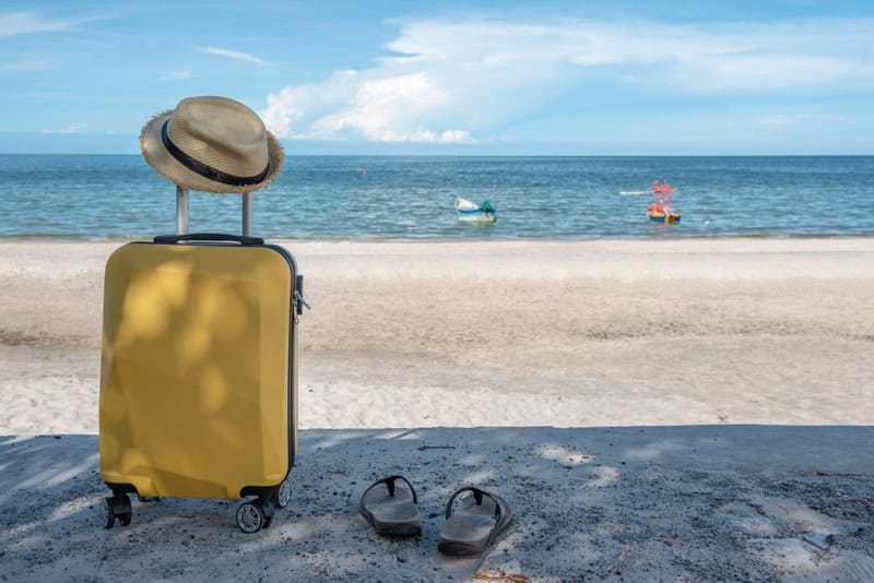 Valise jaune sur une plage ensoleillée, symbolisant la réduction du poids des images pour améliorer la vitesse d’un site web.