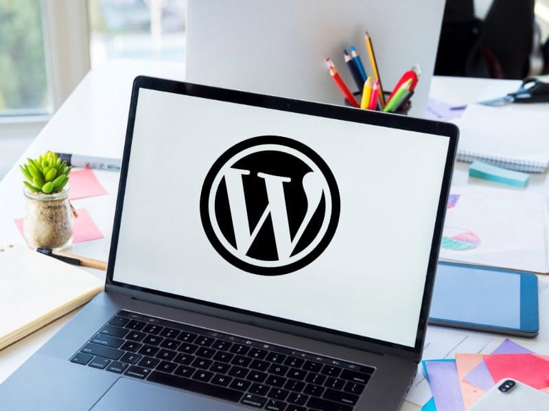 Ordinateur portable affichant le logo WordPress sur un bureau de travail