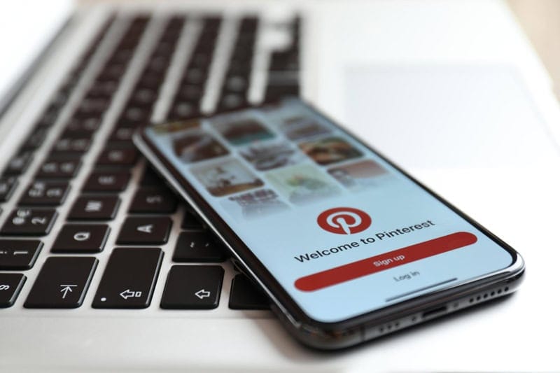 application Pinterest ouverte sur un téléphone posé sur un ordinateur