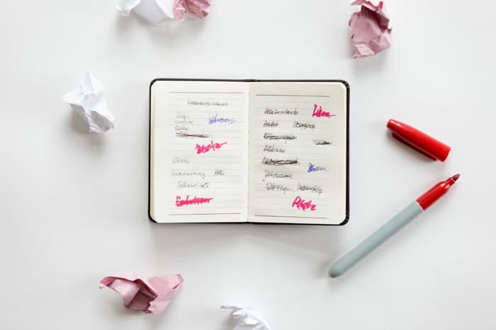 Carnet avec idées barrées et feuilles froissées pour illustrer la recherche d’idées d’articles de blog lifestyle